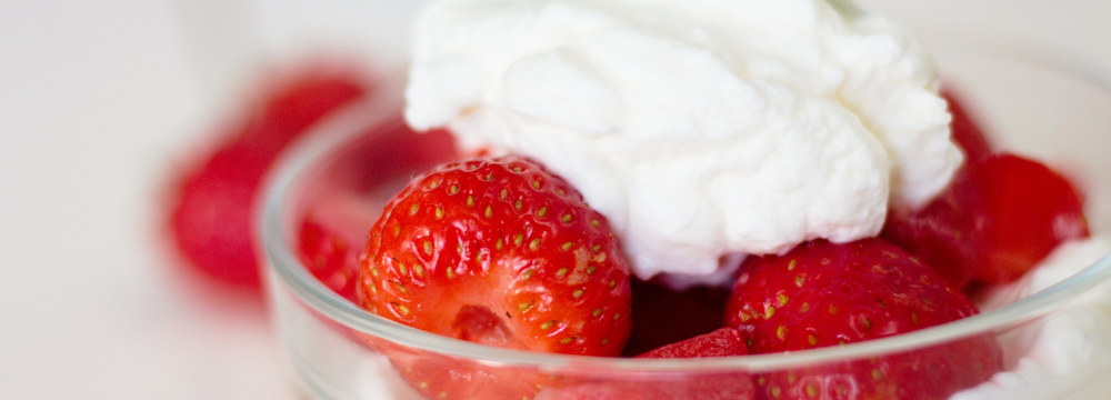 Strawberries and sugar free whipped cream are in a bowl and are a healthy alternative to high sugar treats