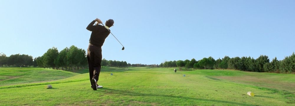 man in backswing teeing off on golf course