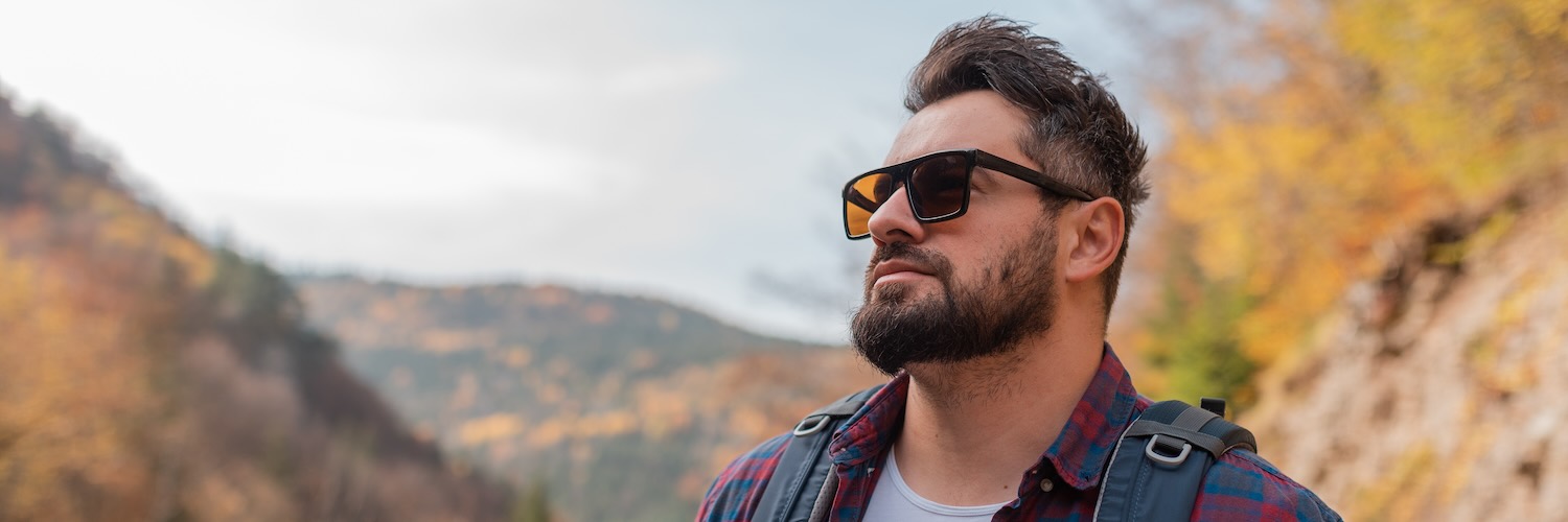 Man in sunglasses hiking the woods looking off in distance 