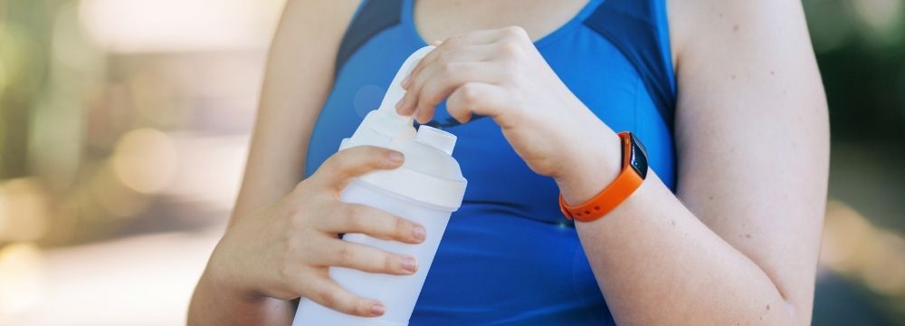 Woman drinks protein shake while on liquids diet after bariatric surgery to improve her weight loss success