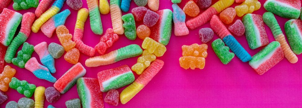 Sugary candy spilled across a pink background illustrates junk food cravings