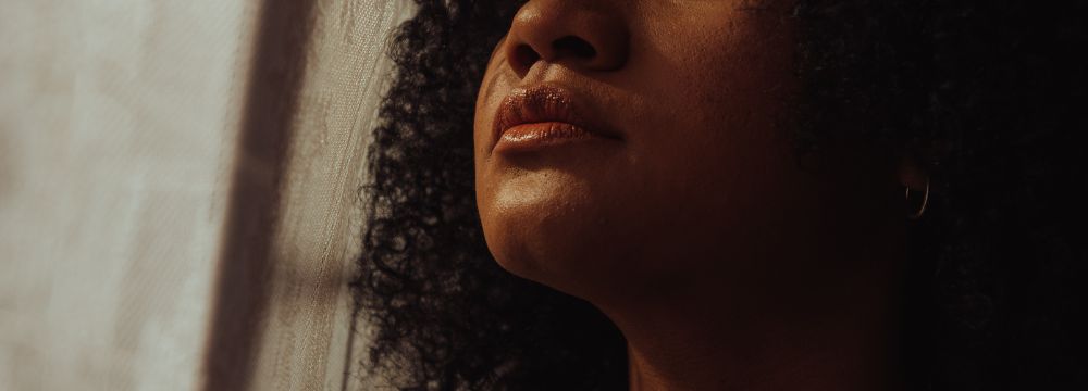 Woman in dark room staring off into distance